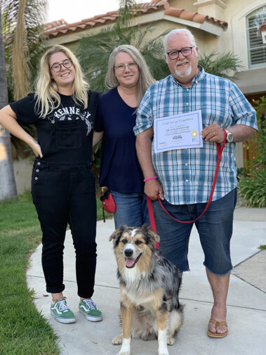 Happy family with their trim-colored Aussie mix, showing off their completion certificate.