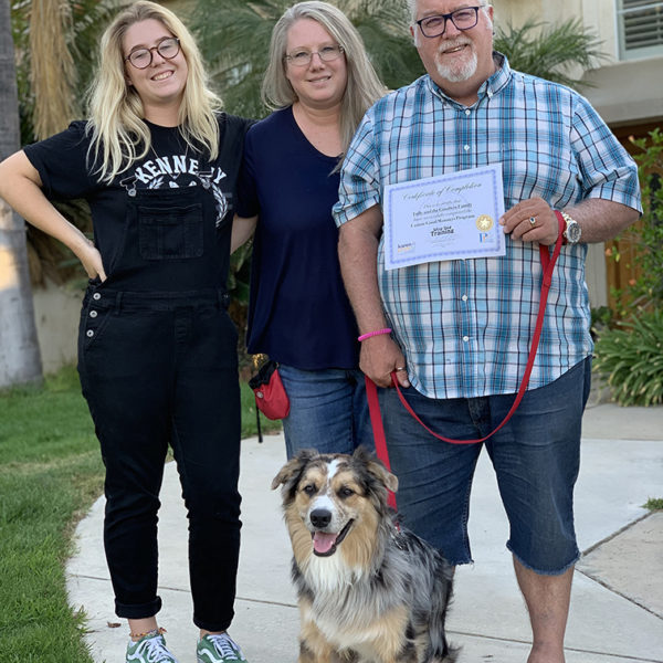 Happy family with their trim-colored Aussie mix, showing off their completion certificate.