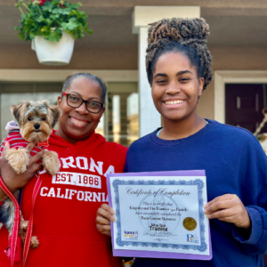 One lady holding her dog, one lady holding up their completion certificate
